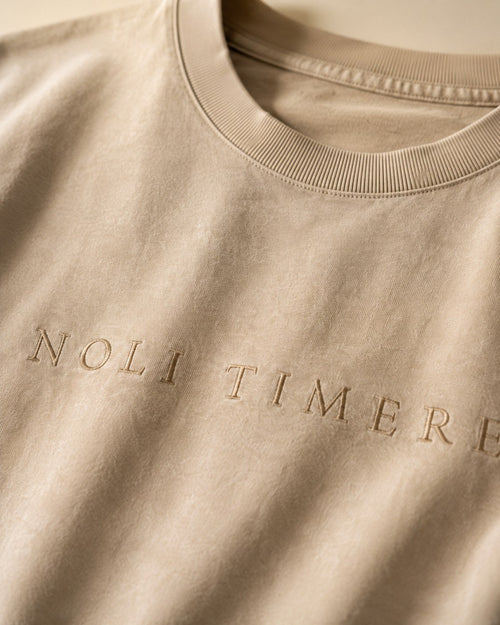 Polera Lavada 280 gr · Beige - detalle del bordado NOLI TIMERE